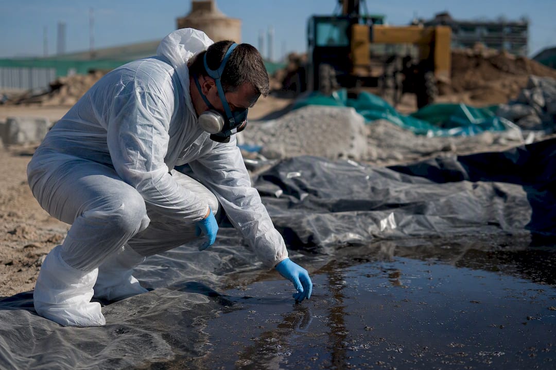 Technician in protective gear testing contaminated wall