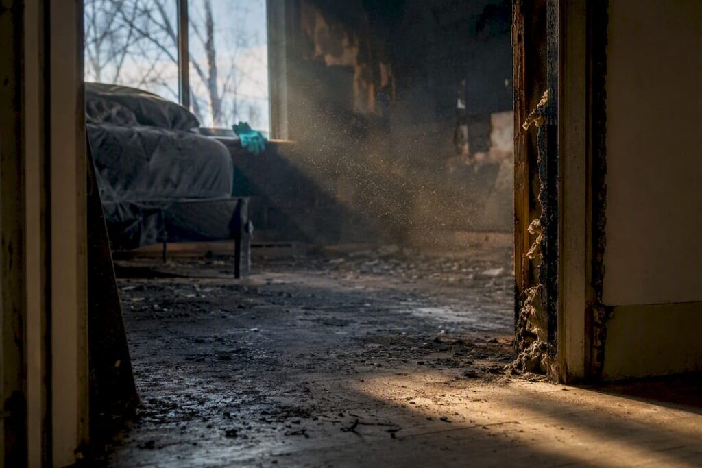 Ash particles visible inside fire-damaged bedroom