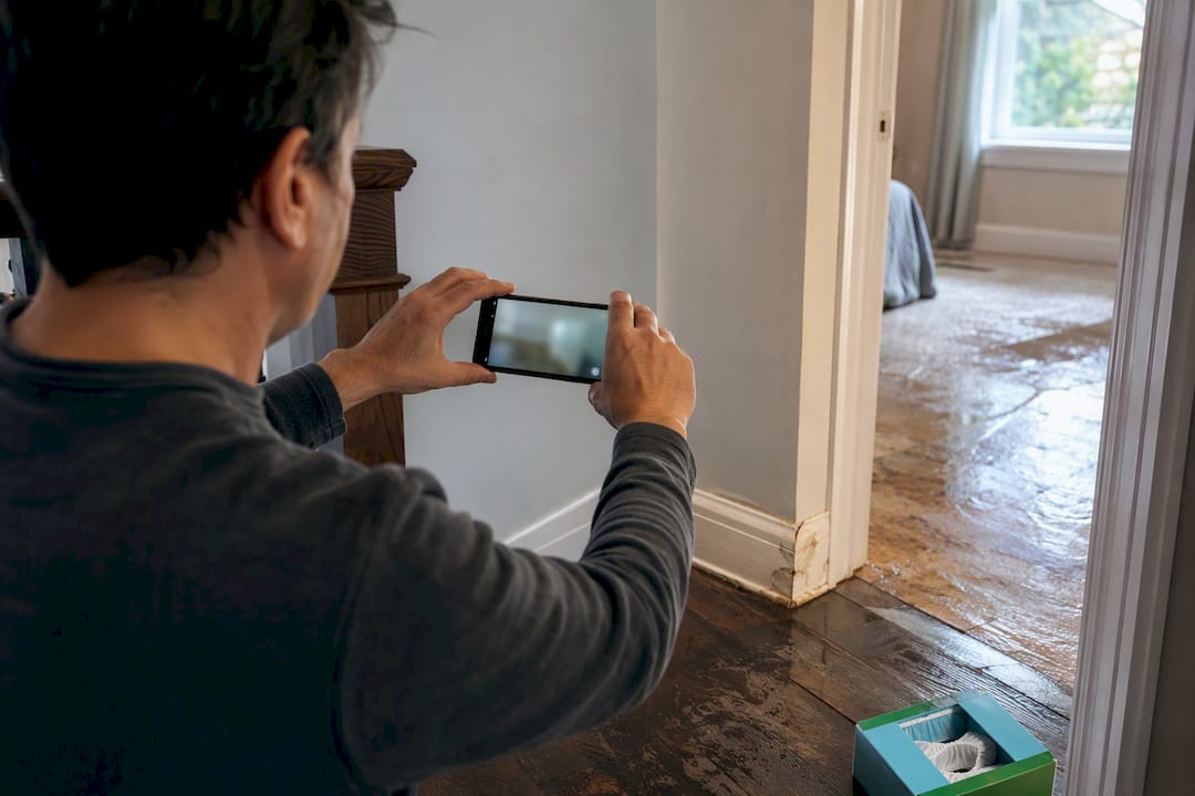 Homeowner filming wet flooring for insurance